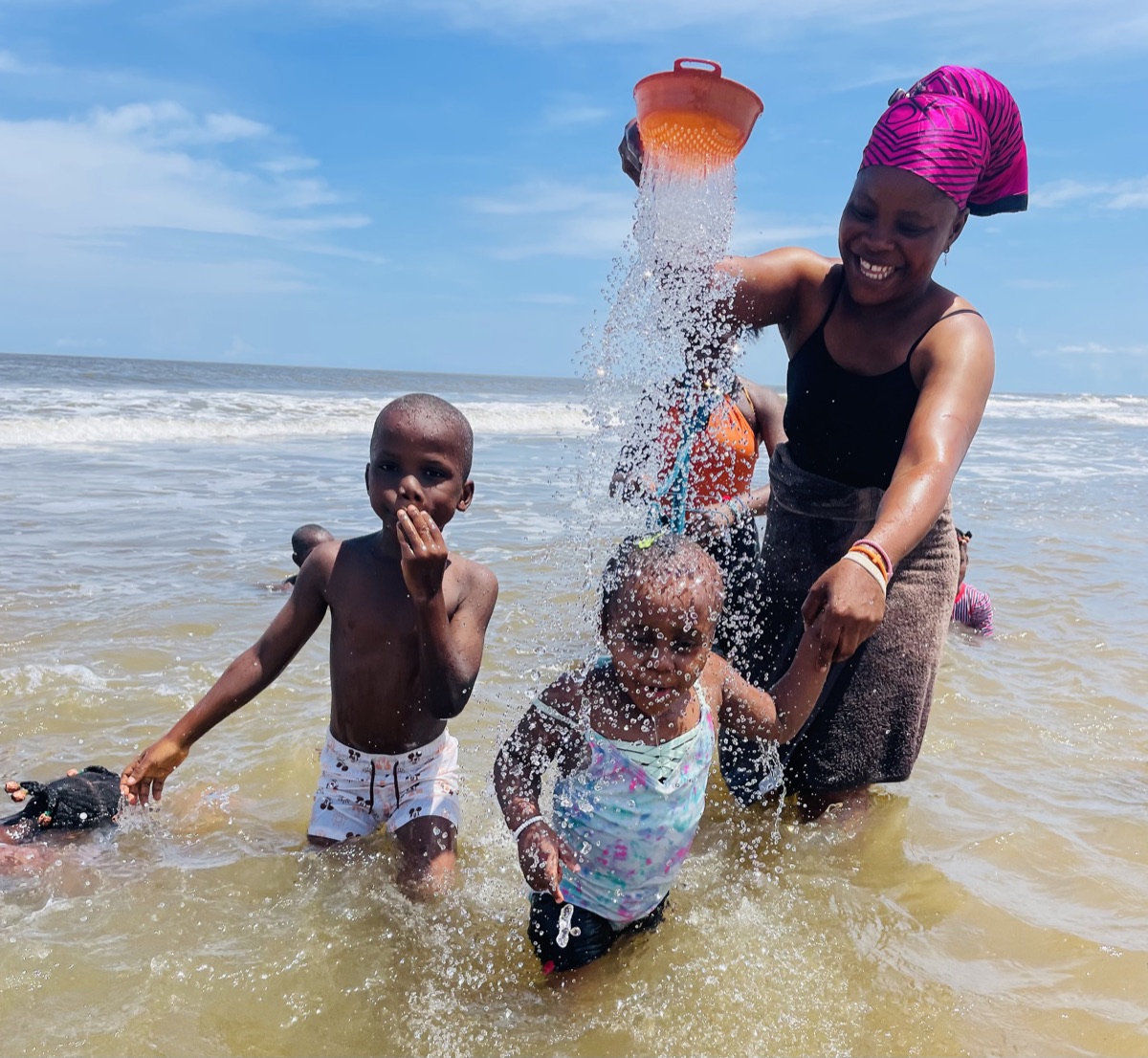 Children playing in the surf with a caregiver in Liberia